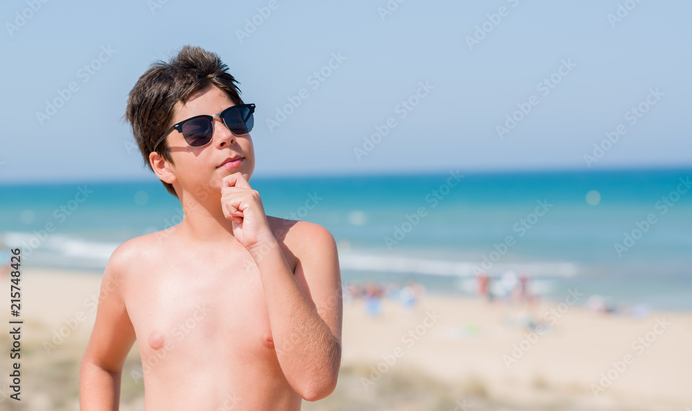 Young child on holidays at the beach serious face thinking about question, very confused idea Young child on holidays at the beach serious face thinking about question, very confused idea
