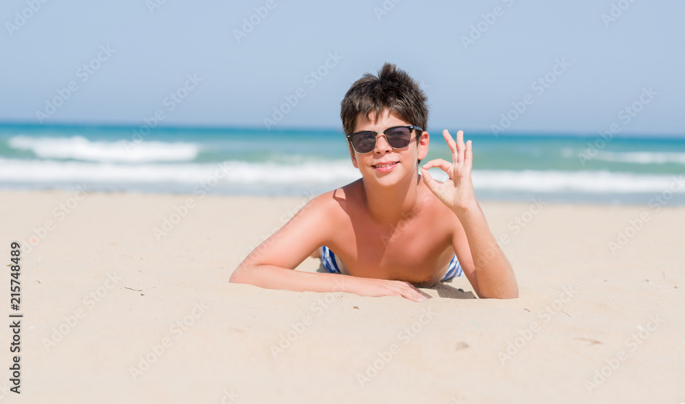 Young child on holidays at the beach doing ok sign with fingers, excellent symbol Young child on holidays at the beach doing ok sign with fingers, excellent symbol