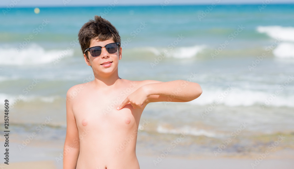 Young child on holidays at the beach with surprise face pointing finger to himself Young child on holidays at the beach with surprise face pointing finger to himself