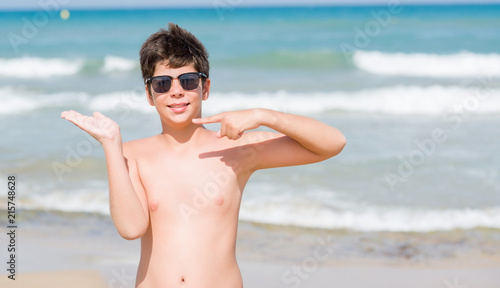 Young child on holidays at the beach very happy pointing with hand and finger