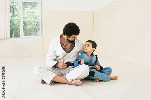 Male karate instructor training little child in dojo or jiu-jitsu at gym at tatami. Father and son are preparing for training. Sport and healthy family concept