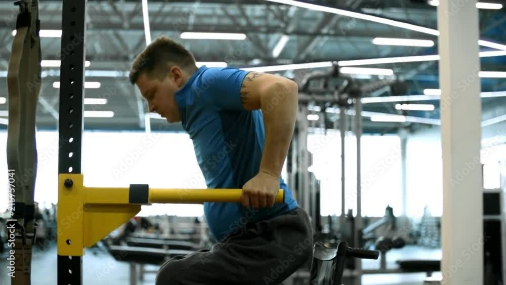 PAN of determined paraplegic man in wheelchair doing dips in gym PAN of determined paraplegic man in wheelchair doing dips in gym