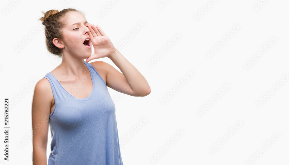 Young blonde woman shouting and screaming loud to side with hand on mouth. Communication concept. Young blonde woman shouting and screaming loud to side with hand on mouth. Communication concept.