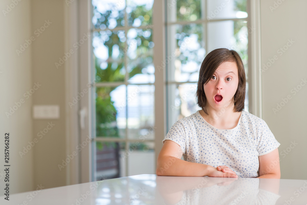 Down syndrome woman at home scared in shock with a surprise face, afraid and excited with fear expression