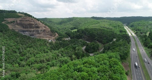 Cars commuting on highway adjacent to rocky mountainside.