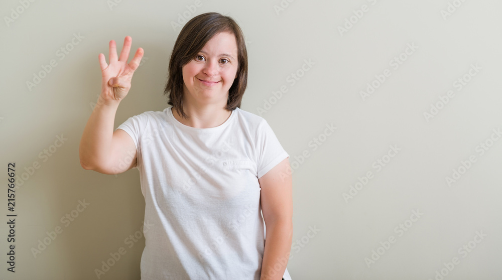 Down syndrome woman standing over wall showing and pointing up with fingers number four while smiling confident and happy. Down syndrome woman standing over wall showing and pointing up with fingers number four while smiling confident and happy.