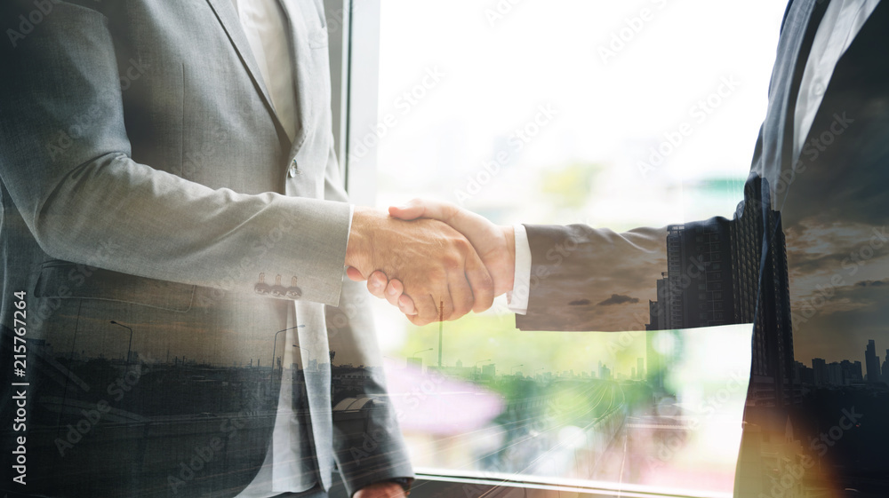 double exposure of businessman shaking hands with business deals with city backgrounds