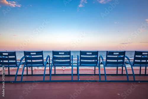 Stampa su tela Mediterranean Sea and famous blue chais on Promenade des Anglais at sunset in Ni