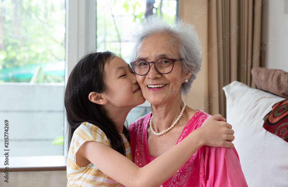 Portrait of cute little girl and her beautiful grandma sitting on sofa at  home ,Asian girl kissing her smiling granny in cheek Stock Photo | Adobe  Stock