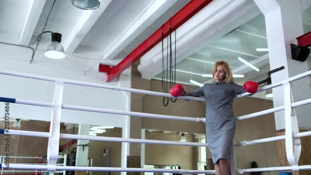 Beautiful businesswoman in elegant dress and boxing gloves at boxing ring Beautiful businesswoman in elegant dress and boxing gloves at boxing ring