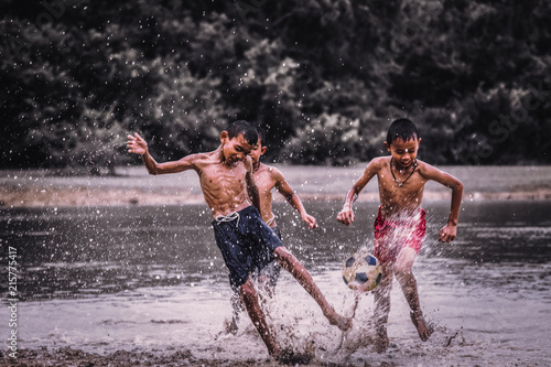 Boys play football on a muddy waters