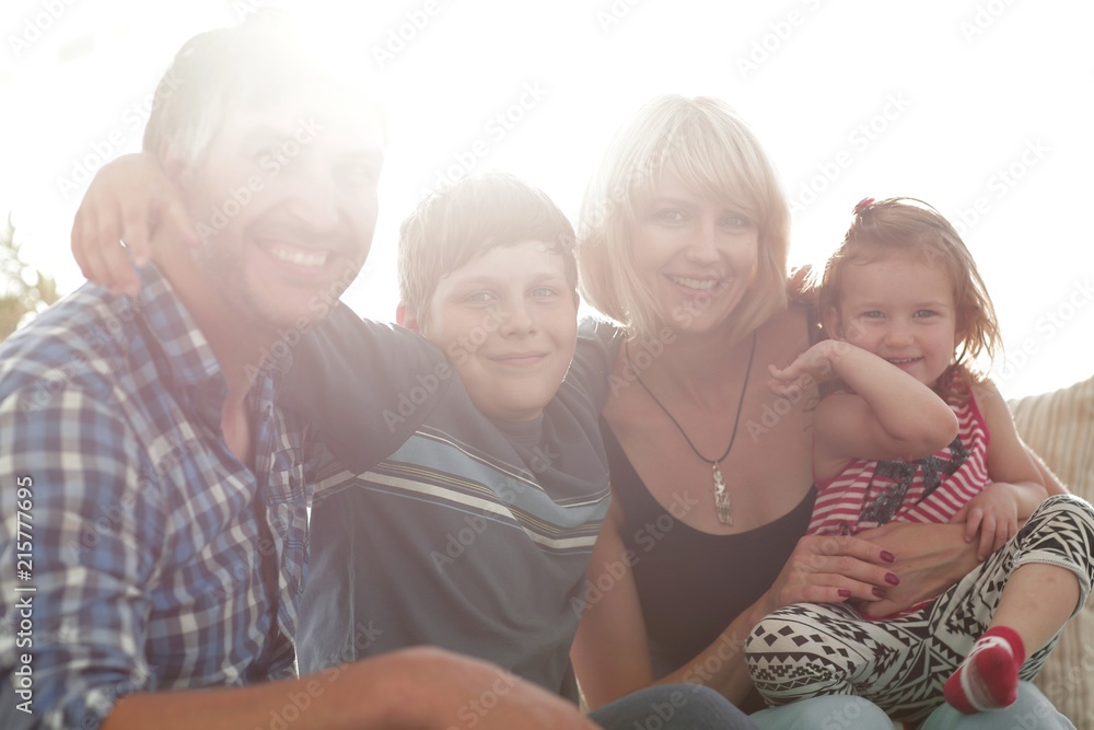 family with two children sitting together and looking at camera family with two children sitting together and looking at camera