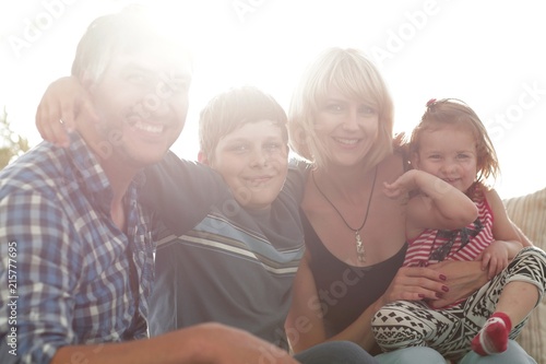 family with two children sitting together and looking at camera