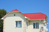 Guttering with red metal house roof. Roof guttering pipeline system.