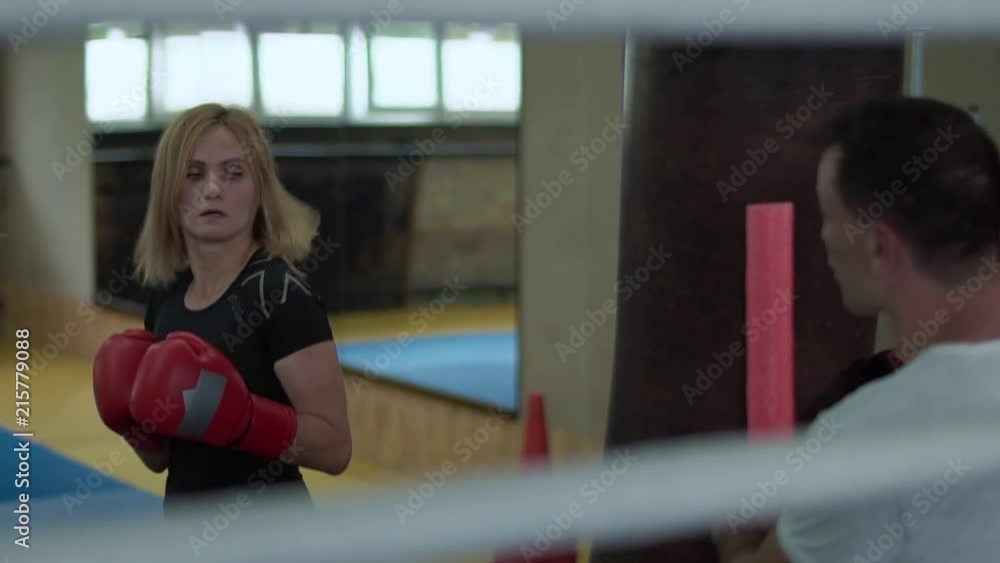 Woman wearing boxing gloves training with punchbag Woman wearing boxing gloves training with punchbag