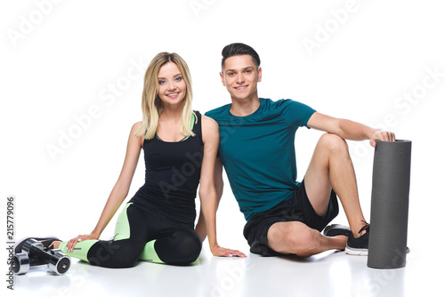 fit young couple in sportswear sitting on floor isolated on white