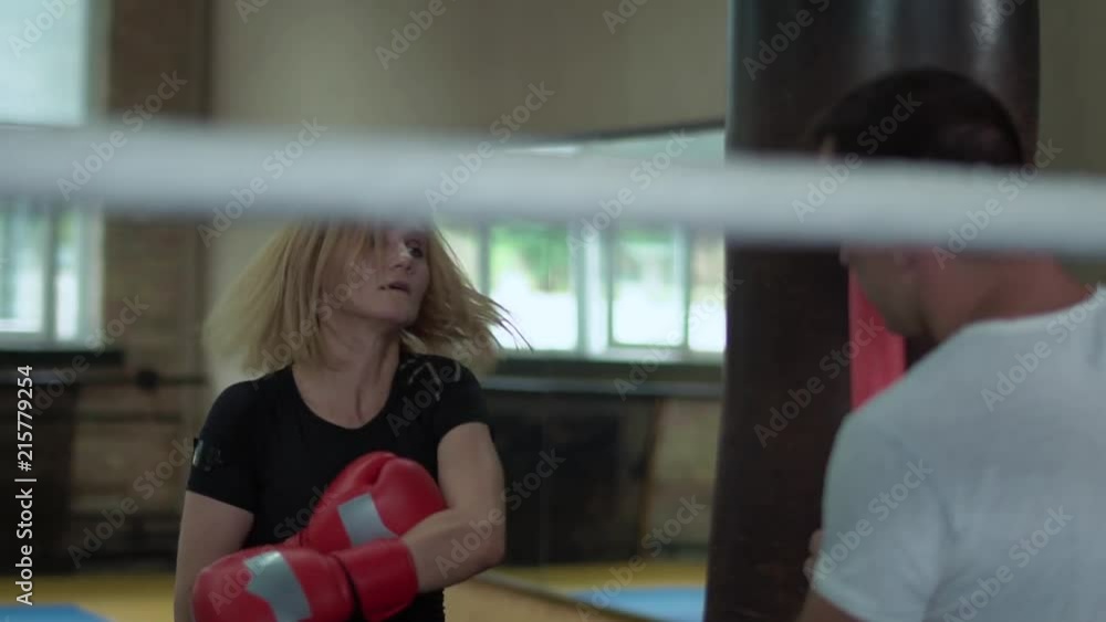 Pretty strong woman work out the blows with punchbag in the gym Pretty strong woman work out the blows with punchbag in the gym