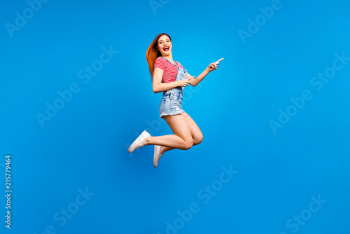 Full-size excited cheerful careless girl demonstrating empty place isolated on vivid blue background with copy space for text