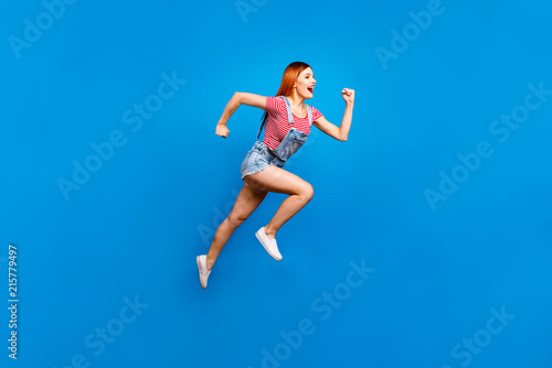 Fototapeta Naklejka Na Ścianę i Meble -  Full-size portrait of running marathon girl who looks in front of her isolated on bright blue background