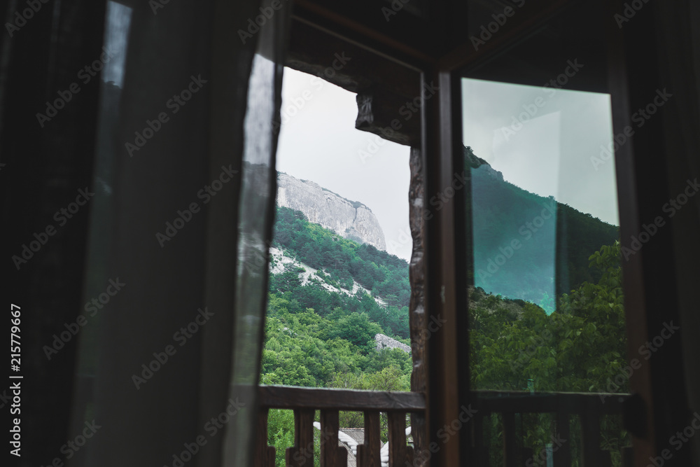 Mountain view through open window on balcony, rocks in cloudy and foggy weather Mountain view through open window on balcony, rocks in cloudy and foggy weather