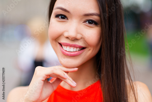 Crop photo close up portrait of charming young woman with toothy beaming smile looking at camera touching the chin by hand