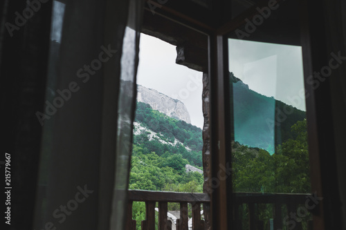 Mountain view through open window on balcony  rocks in cloudy and foggy weather