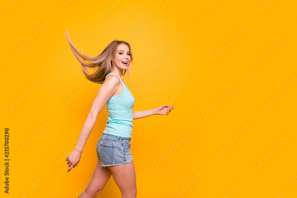 Φωτογραφία Cute straight-haired blonde caucasian smiling girl, wearing casual blue shirt and jeans shorts, going, walking, wind blows hair