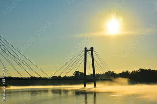 Beautiful landscape. Fog over the river at sunrise. Silhouette of a cable-stayed bridge. Reflection of the sun in water. Krasnoyarsk. Siberia. Russia. Yenisei
