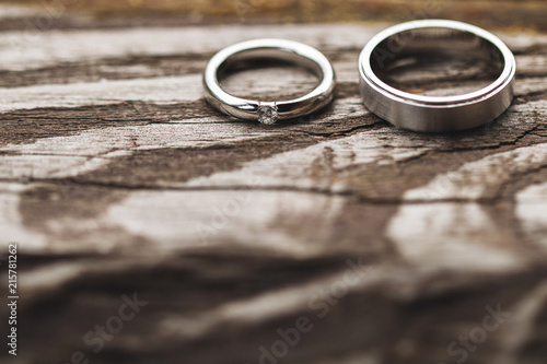 Jewelry shot of wedding rings on wooden texture with shadows of tropical leaves. Beautiful light