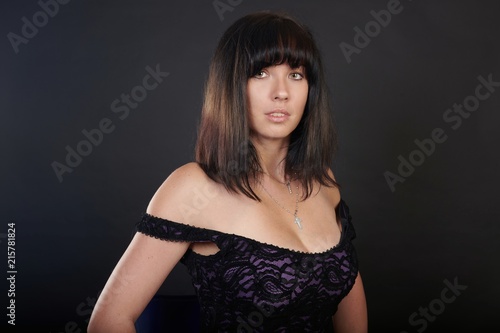 Trendy young brunette woman posing on a high chair, studio shot