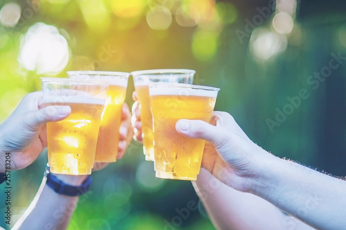 Celebration beer cheers concept - close up hands holding up glasses of beer of people group in outdoor party during their victory competition or successful task meeting