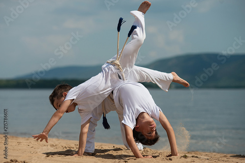 Training of two children on the beach: capoeira, sports