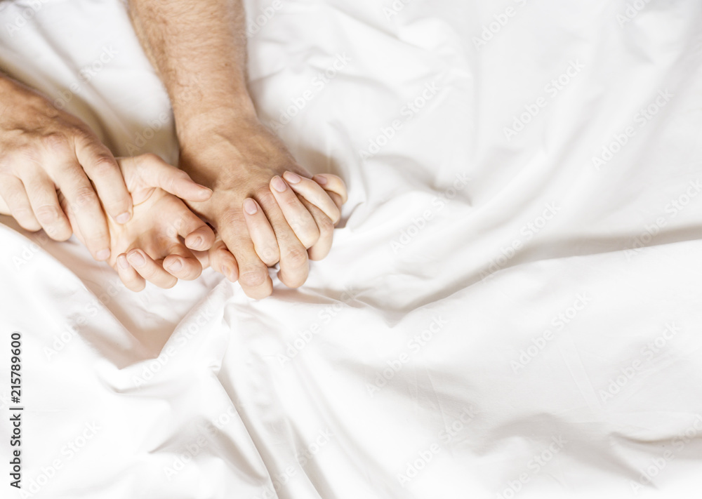Couple having sex. Hand clutches grasps a white crumpled bed sheet in a hotel room, a sign of ecstasy, feeling of pleasure or orgasm - obrazy, fototapety, plakaty 