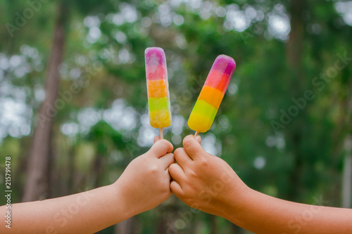 kids hands holding melting ice cream waffle cone in hands on summer light nature background