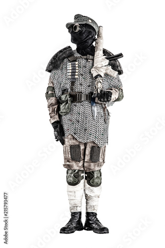 Post apocalyptic soldier in black mask and glasses, wool field cap and handmade armor from car tires and hauberk, standing at attention with submachine gun on shoulder, isolated on white studio shoot photo