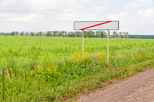 Straight road and white empty sign with red line on roadside at the town gates against beautiful summer landscape background. Bolshaya Doroga village, Tambovsky region, Russia.
 photo