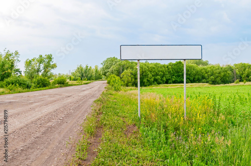 Straight road with white empty sign on roadside at the entrance to the city against beautiful summer landscape background. Bolshaya Doroga village  Tambovsky region  Russia.