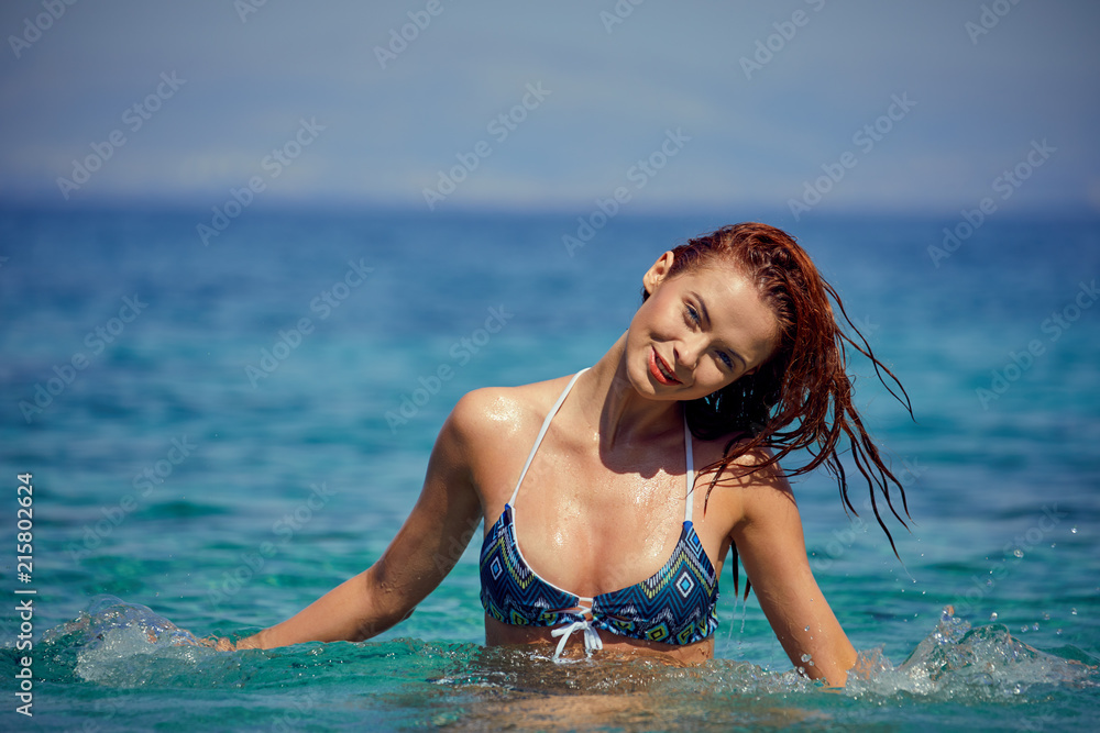 Pretty beautiful woman in white swimwear bikini posing in blue sea water Pretty beautiful woman in white swimwear bikini posing in blue sea water