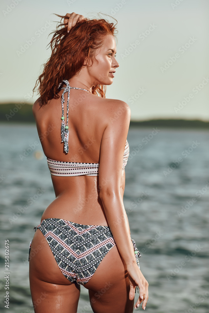 Pretty beautiful woman in white swimwear bikini posing in blue sea water Pretty beautiful woman in white swimwear bikini posing in blue sea water