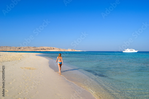 woman walking on beach of Mahmya island with turquoise water, Egypt