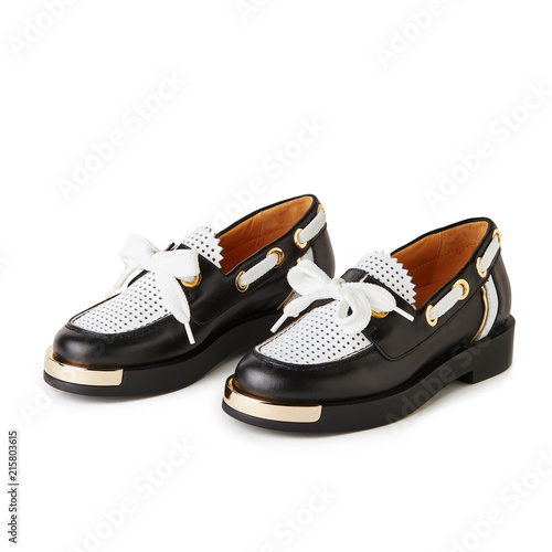 Elegant black and white loafers shoes with golden details. Studio shot, white background