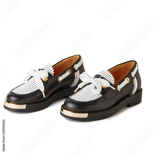 Elegant black and white loafers shoes with golden details. Studio shot, white background