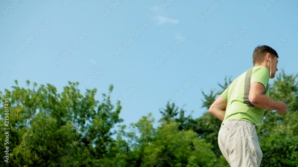 Mature man fitness is engaged in the bek in the open air, in headphones. Super slow motion Mature man fitness is engaged in the bek in the open air, in headphones. Super slow motion