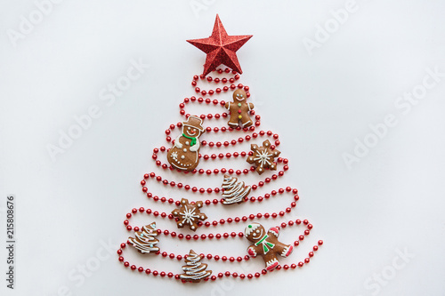 Creative idea in minimalistic style for Christmas or New Year themes. A Christmas tree made of beads decorated with ginger cookies and a star on top. Celebratory concept.