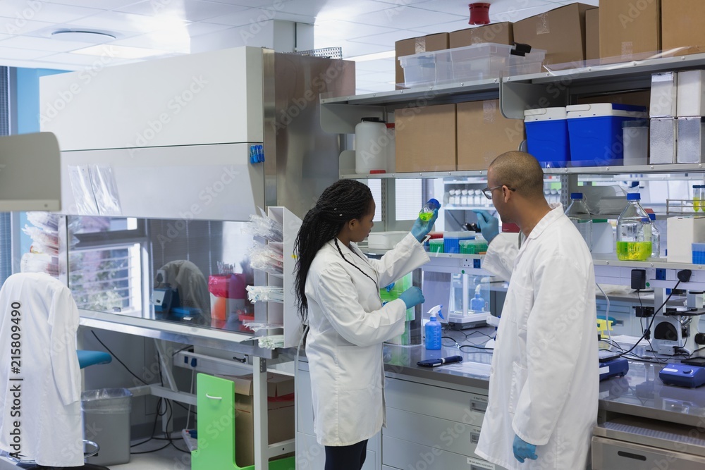 Scientists discussing over chemical solution in bottle Scientists discussing over chemical solution in bottle