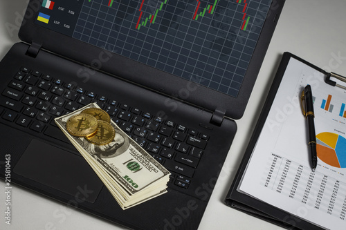 Gold coin in the form of bitcoin with dollars on a black laptop