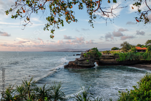 Sacred Balinese temple Tanah Lot. Pura Batu Bolong on the edge of a cliff at coastline with hole in the rock. Traditional style and architecture of Bali. Holy place for local indonesian people