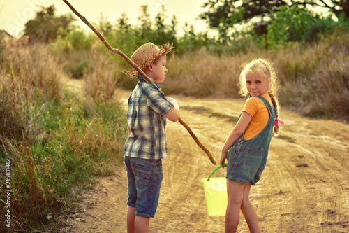 funny children go fishing in the summer evening on a dirt road . Children on active rest