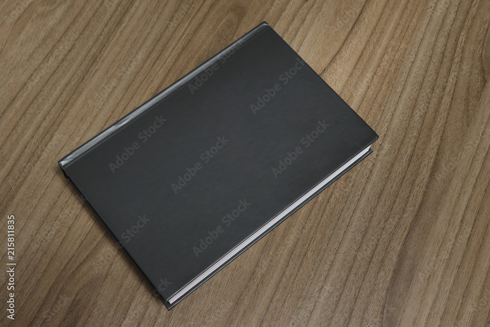 Black hardcover book on wooden surface - mock-up black book Black hardcover book on wooden surface - mock-up black book