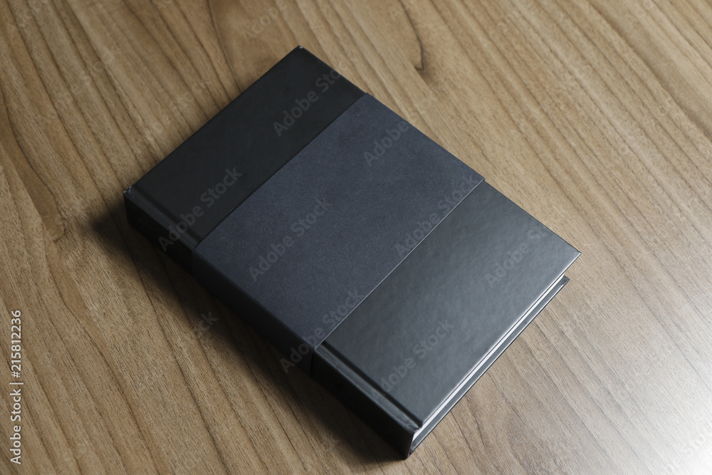 Black hardcover book with protector on wooden surface - mock-up black book